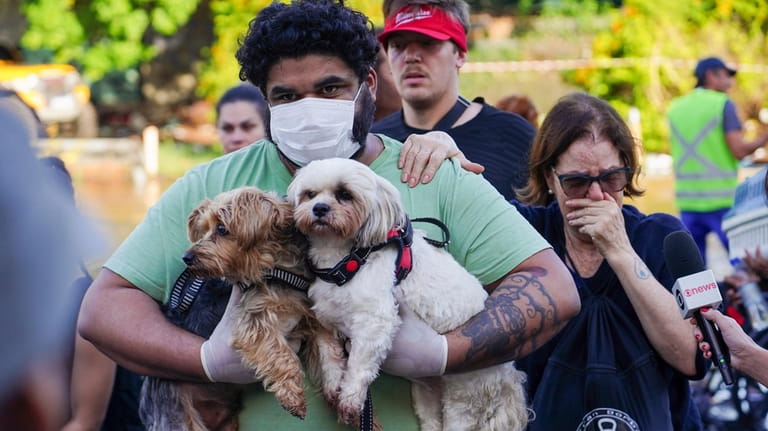 A resident carries his pets as he evacuates from a...