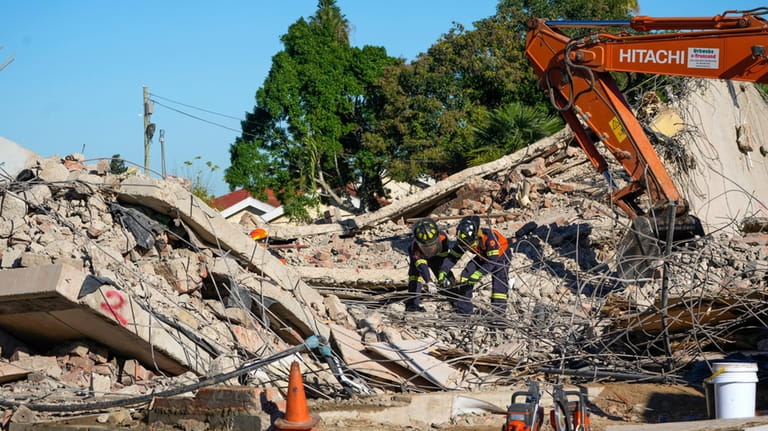 Rescue personnel search the site of a building collapse in...
