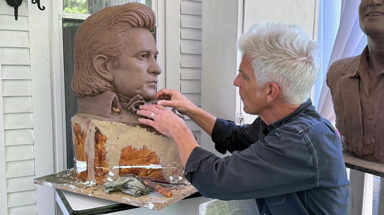 Artist Kevin Kresse, works on a clay bust of Johnny...