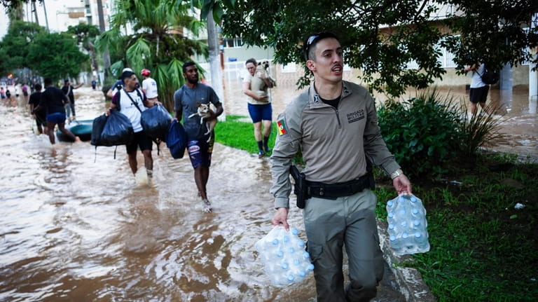 A military police carries water bottles for flood victims after...