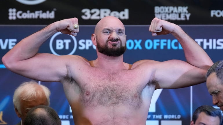 British heavyweight boxers Tyson Fury shows his muscles during weigh-in...