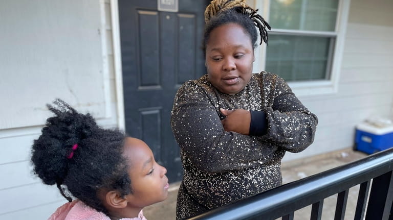 Tameka and her 8-year-old daughter talk on their porch in...