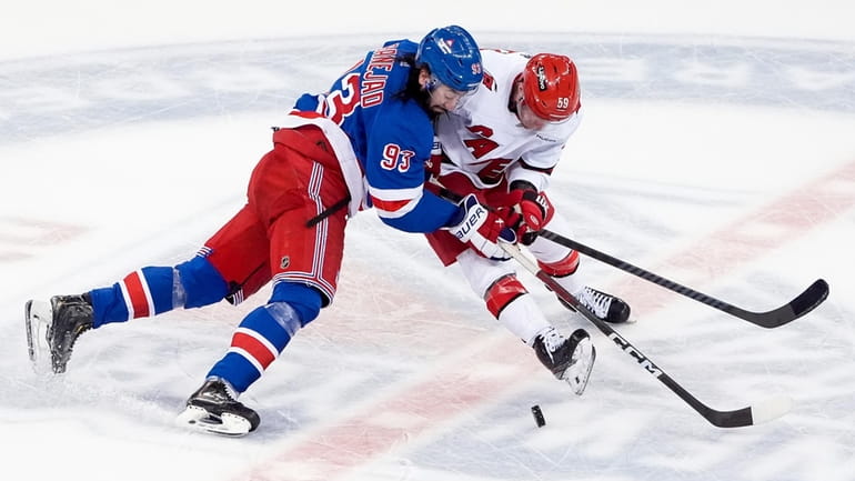 Hurricanes center Jake Guentzel and Rangers center Mika Zibanejad fight for the...