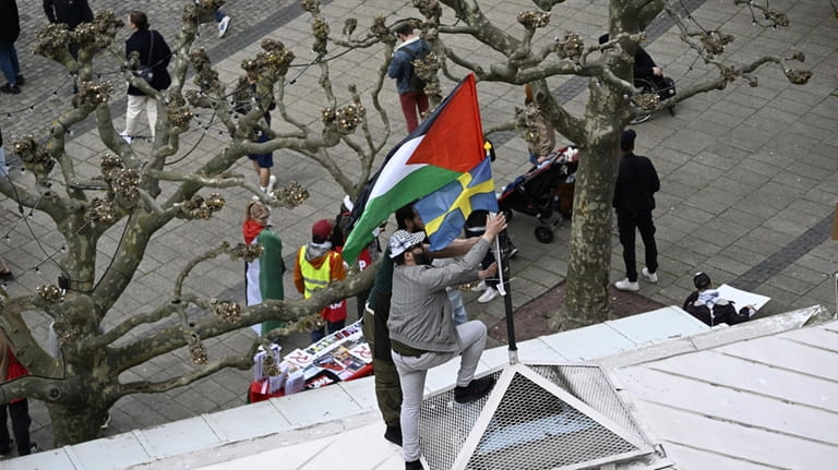 Protestors fix a Palestinian and Swedish flag atop of a...