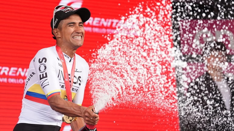 Jhonatan Narváez celebrates with sparkling wine on podium after winning...
