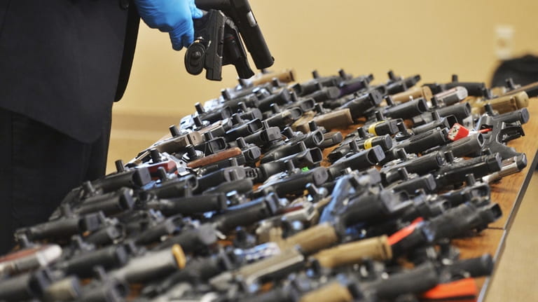 Dozens of recovered stolen handguns are displayed during a press...