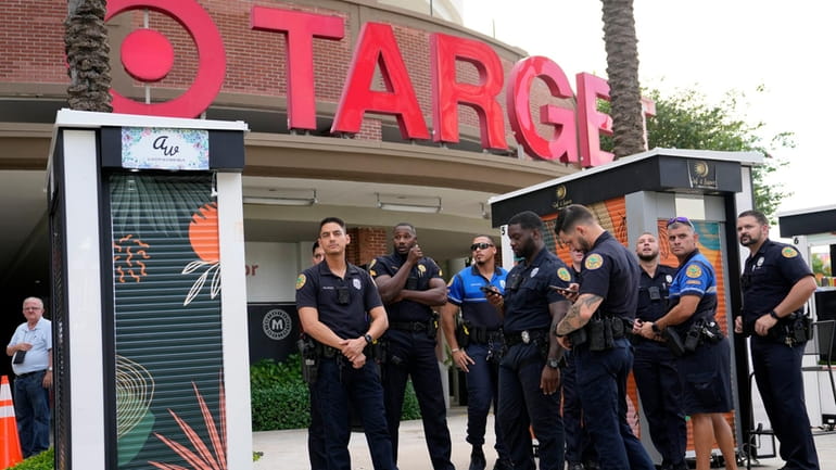 Police officers stand outside of a Target store as a...