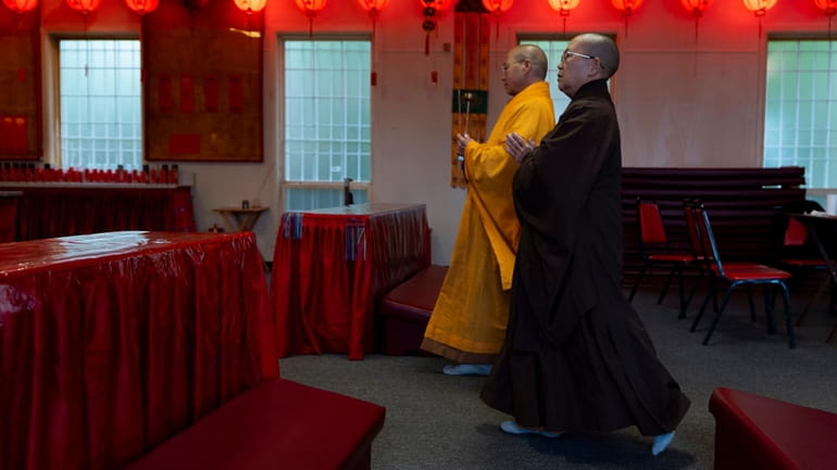 Monk Dauv Singx Si, left, walks towards an altar at...