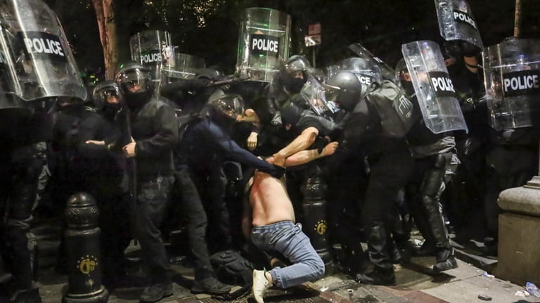 Riot police detain a demonstrator during an opposition protest against...
