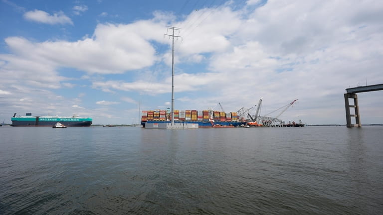 A vessel, left, moves past the stranded container ship Dali,...