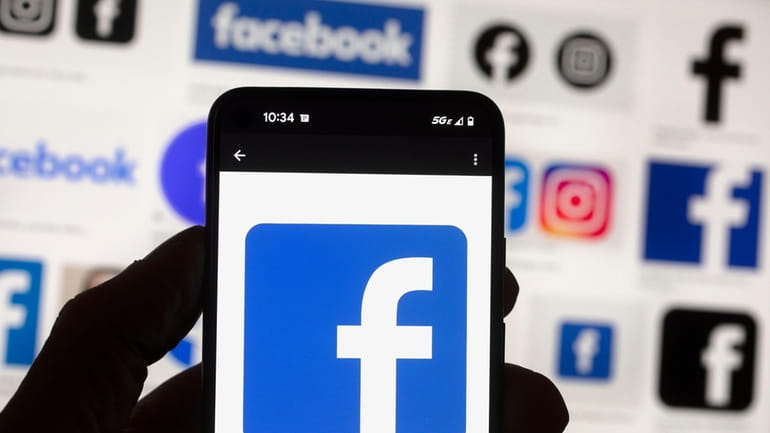 The Facebook logo is seen on a cell phone in...