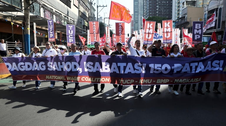Filipino workers carry streamers and posters during a protest to...