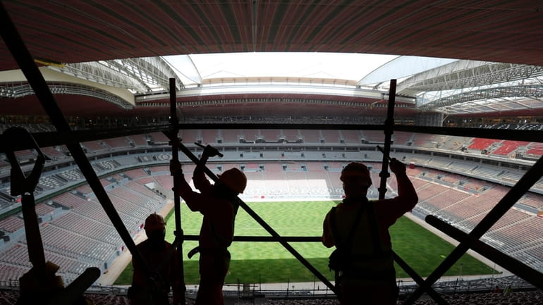 Laborers remove scaffolding at the Al Bayt stadium in Al...
