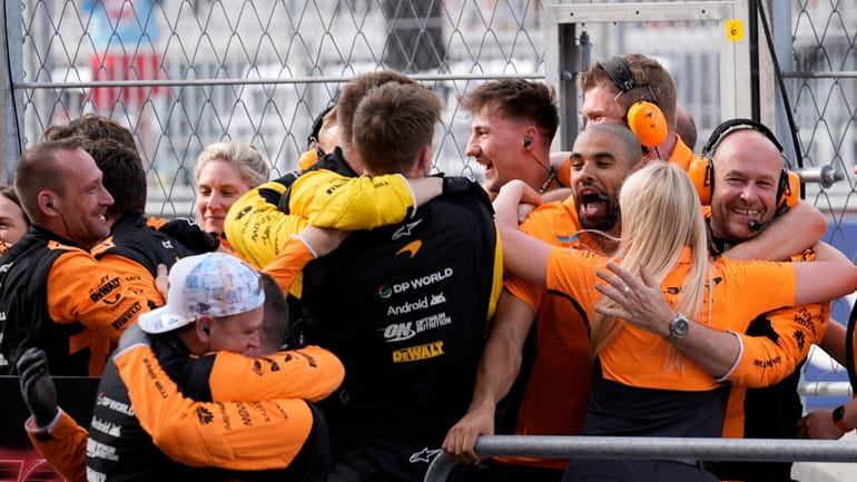 McLaren pit crew members celebrate after McLaren driver Lando Norris,...