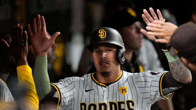 San Diego Padres' Manny Machado is greeted in the dugout...