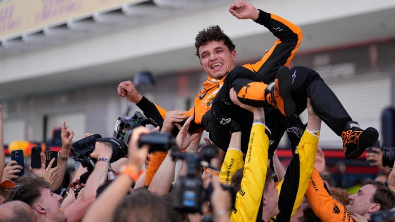 McLaren driver Lando Norris, of Britain, is lifted after winning...