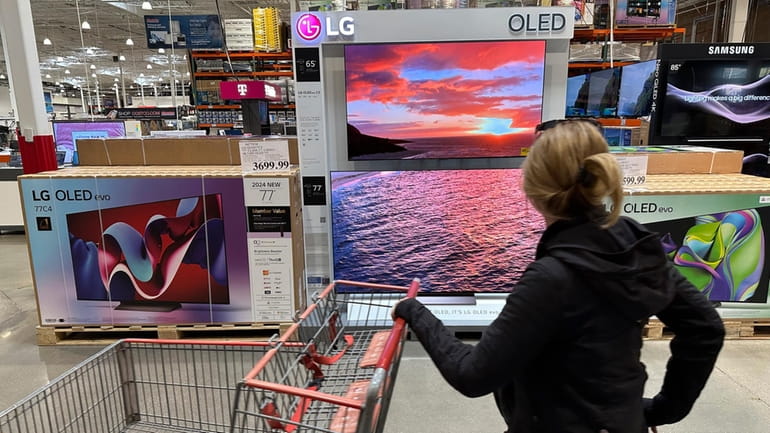 A shopper passes a display of televisions at a Costco...