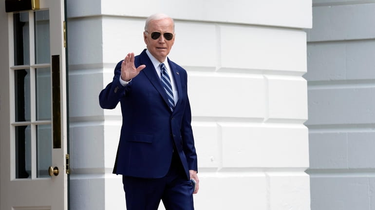 President Joe Biden waves as he walks out of the...