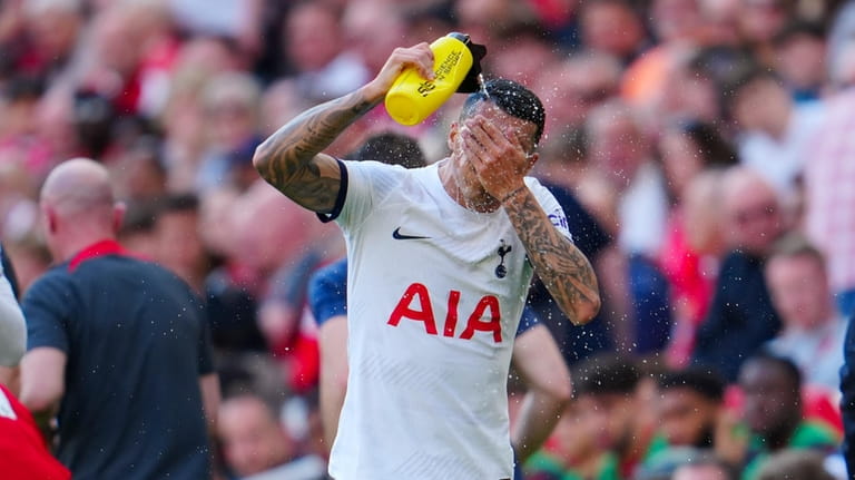 Tottenham's Pedro Porro splashes water on his face during the...