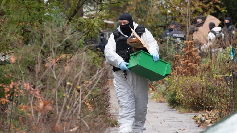 A police officer carries a plastic box during a raid...