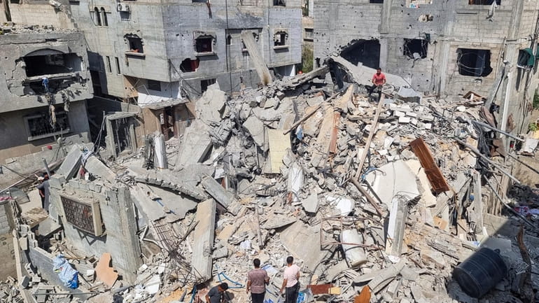 Palestinians look at the destruction after an Israeli airstrike in...