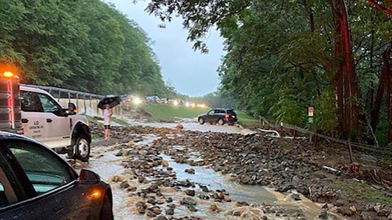 Vehicles come to a standstill near a washed-out and flooded...