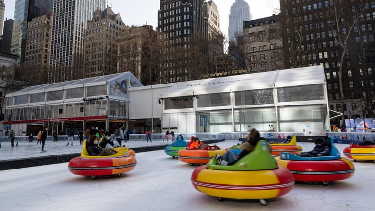 People ride bumper cars on ice at The Rink at...