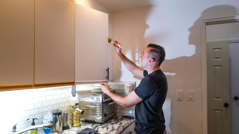Aaron Tomlinson, 26, spruces up the kitchen in his first home,...