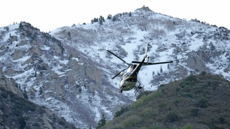 A Utah Department of Public Safety helicopter carries recovery crews...