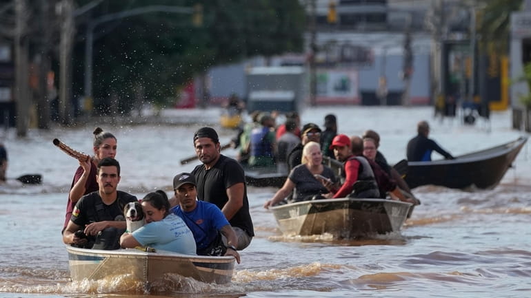 Volunteers help to evacuate residents from an area flooded by...