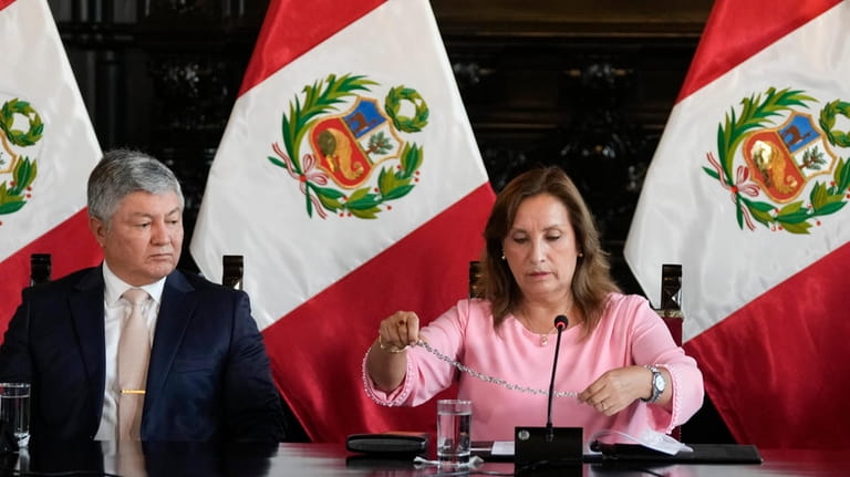 Peruvian President Dina Boluarte shows her necklace, accompanied by her...