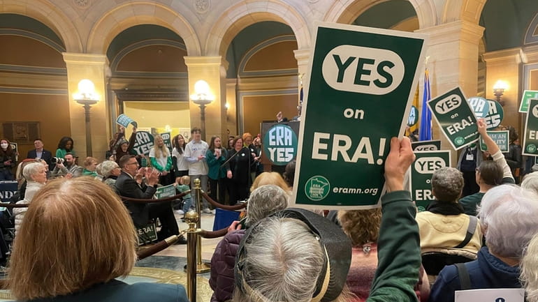 A green sign that says "YES on ERA!" is held...