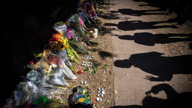 Visitors cast shadows at a memorial to the victims of...