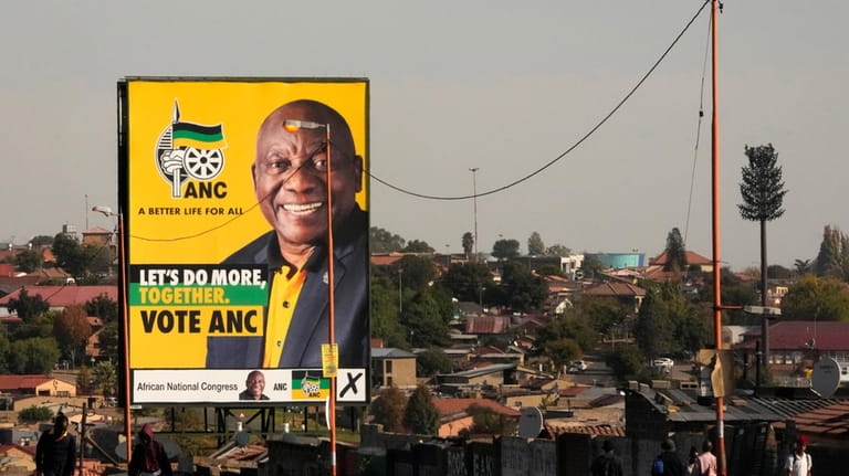 File - An election poster, with President Cyril Ramaphosa atop...