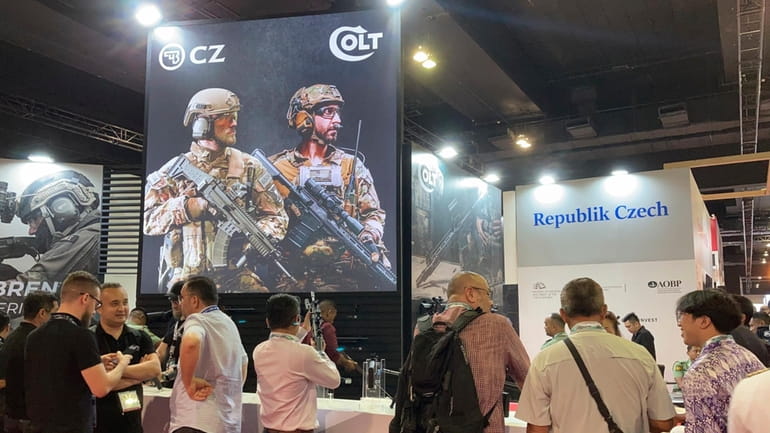 People gather around the booth of Colt, an American firearm...