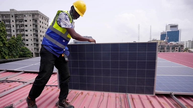 Oladapo Adekunle, an engineer with Rensource Energy, installs solar panels...