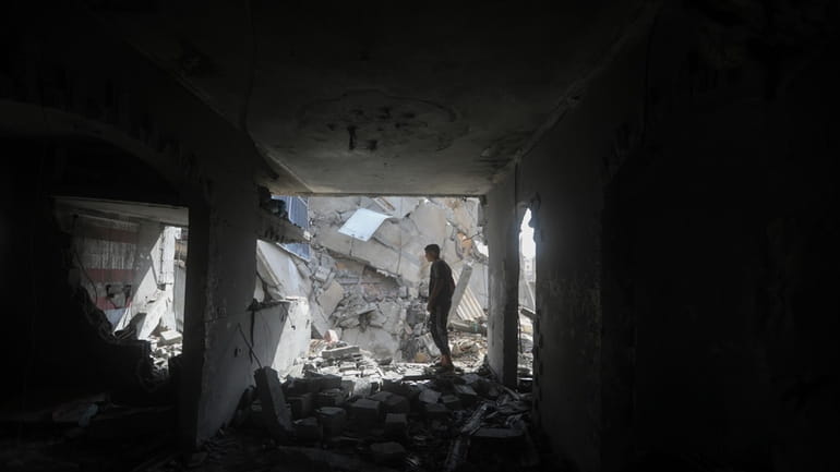 Palestinians look at the destruction after an Israeli strike on...
