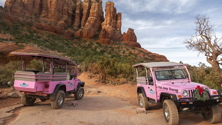 Two Pink Jeep off-road terrain vehicles with tourists touring Broken...