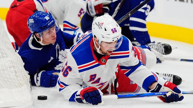 The Rangers' Erik Gustafsson and the Maple Leafs' Mitchell Marner fall to the...