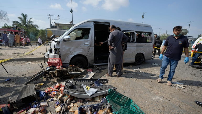Pakistani investigators examine a damaged van at the site of...
