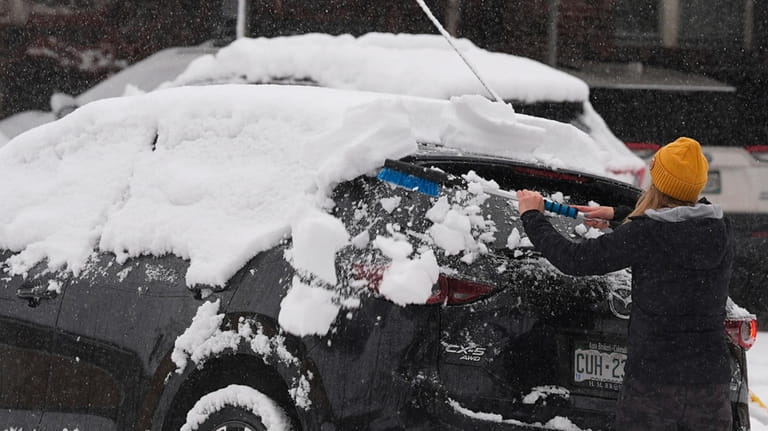 A motorist clears snow from her all-wheel-drive vehicle as a...