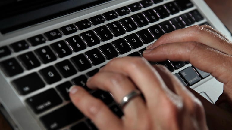 A person works on a laptop in North Andover, Mass.,...