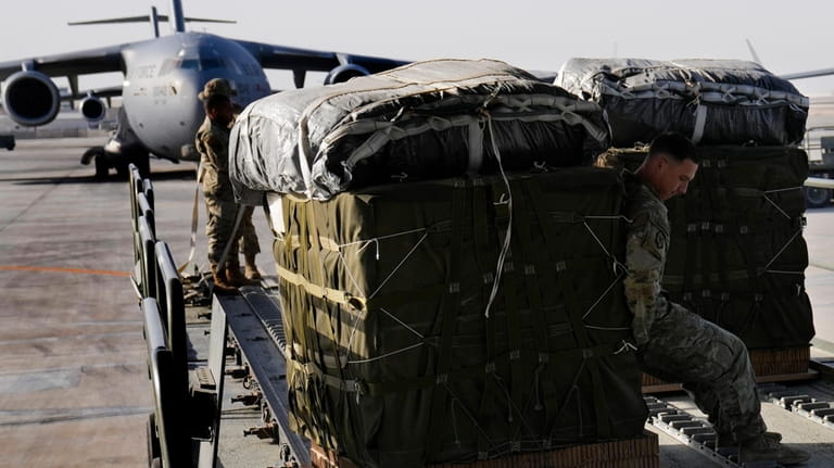 A member of the U.S. Air Force loads containers of...
