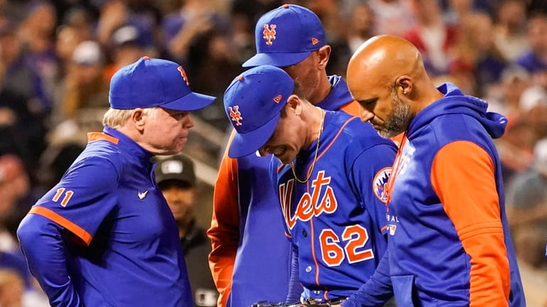 Mets pitcher Drew Smith walks off the field with with manager...