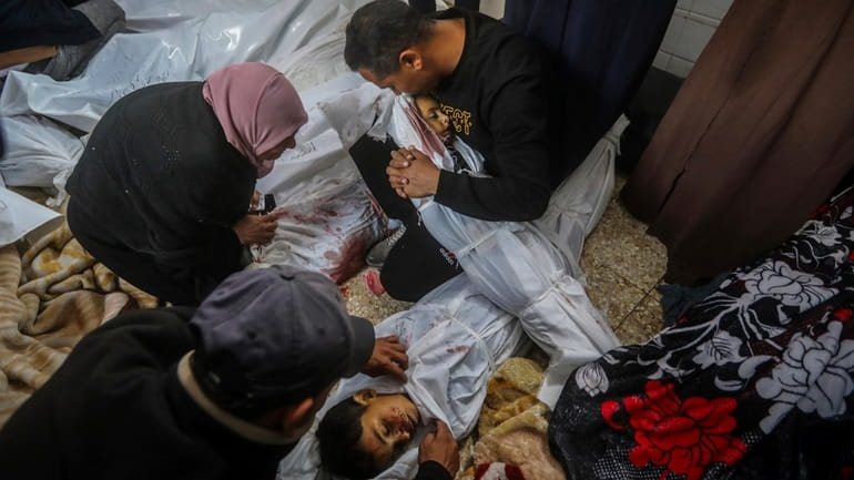 Palestinians mourn over the bodies of their relatives killed in...