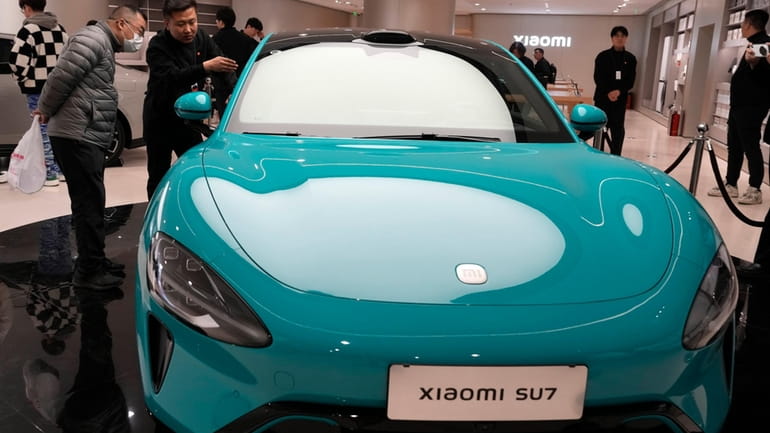 Visitors to the Xiaomi Automobile flagship store look at the...