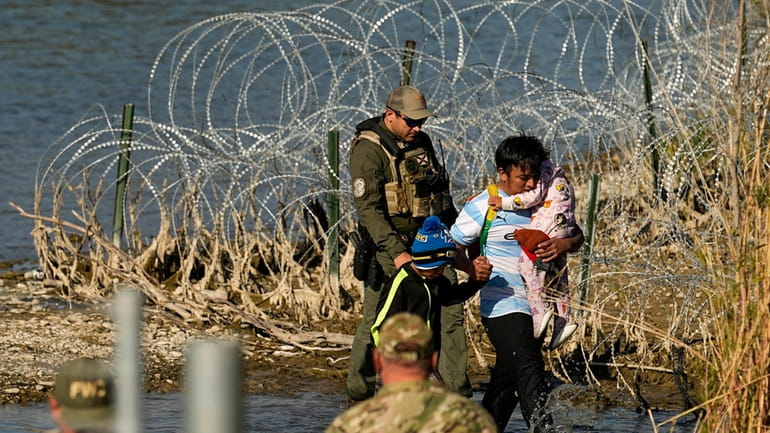 Migrants are taken into custody by officials at the Texas-Mexico...