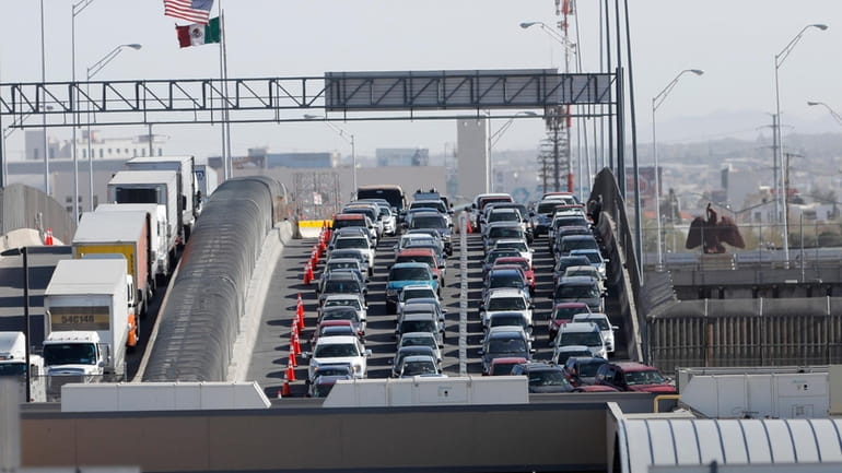 Cars and trucks line up to enter the U.S. from...