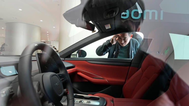 A man peeks at the interior of the Xiaomi SU7...