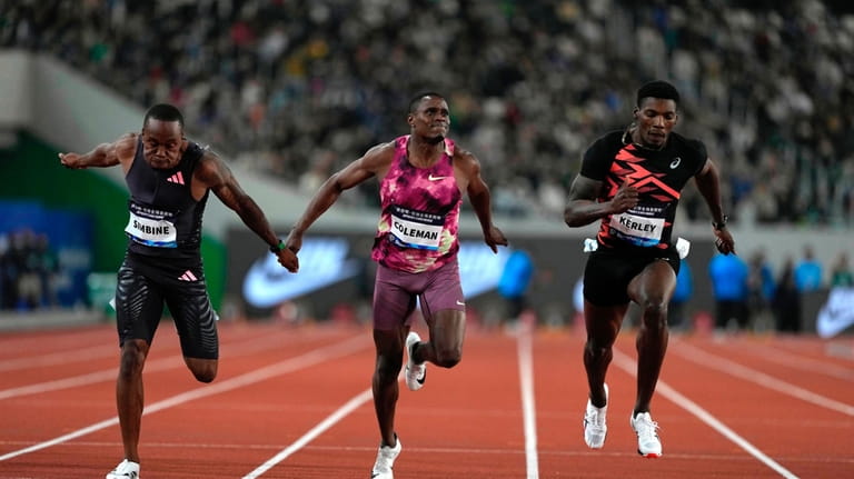 Akani Simbine of South Africa, left, finishes first, with Christian...
